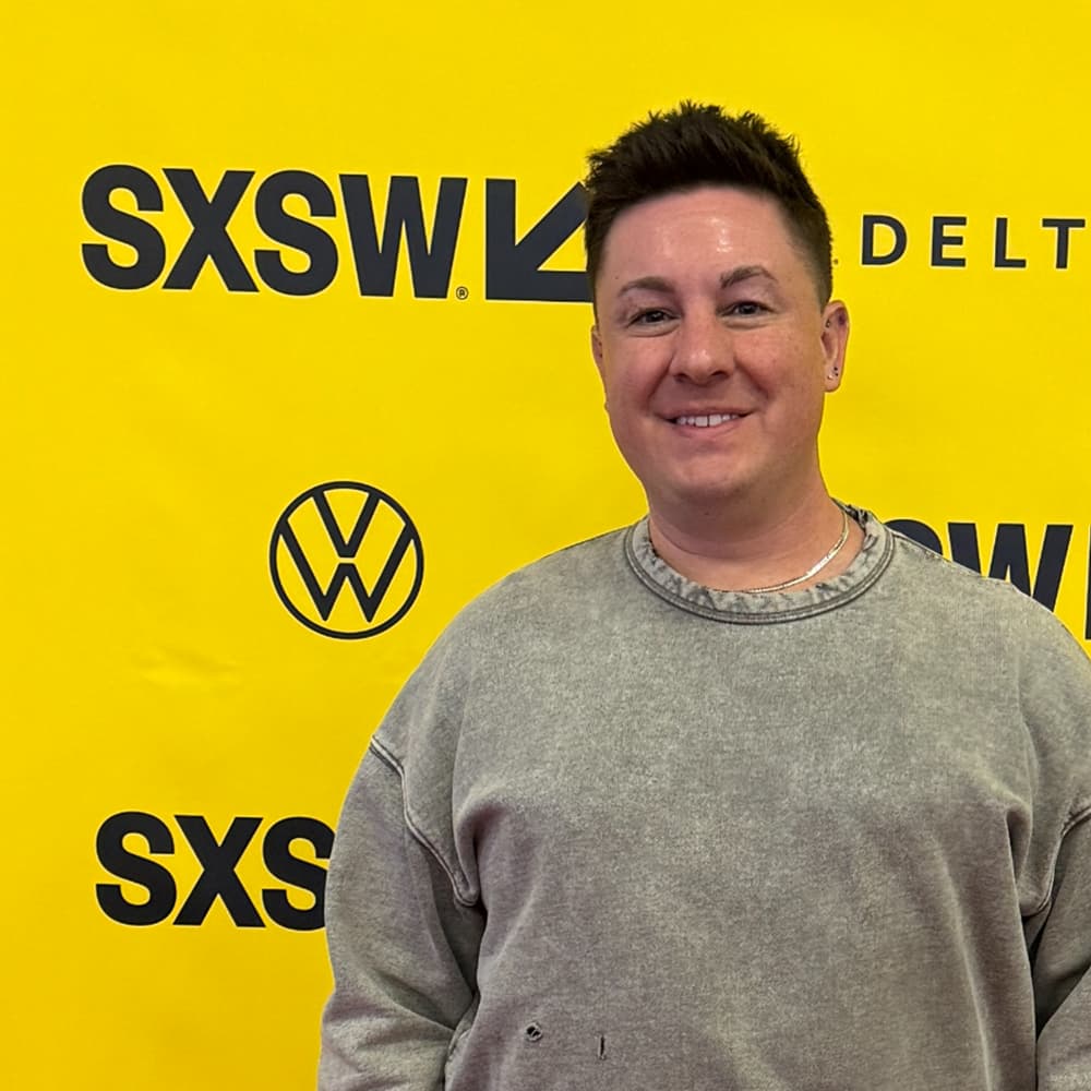 man standing in front of yellow SXSW banner