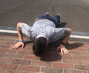 man laying on speedway kissing bricks